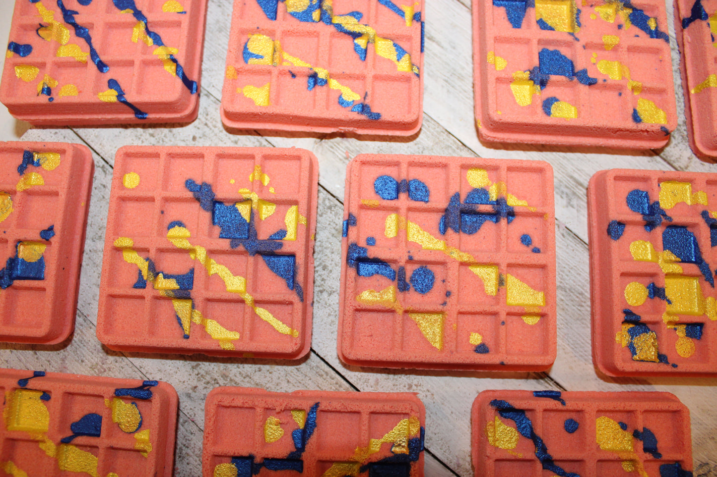 This is a view looking down at the waffle bath bombs to see the bright blue and yellow drizzle.