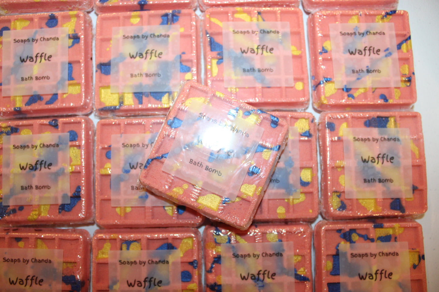 This is another view looking down at the packaging with one waffle bath bomb stacked on top of the others in the center of the photo.