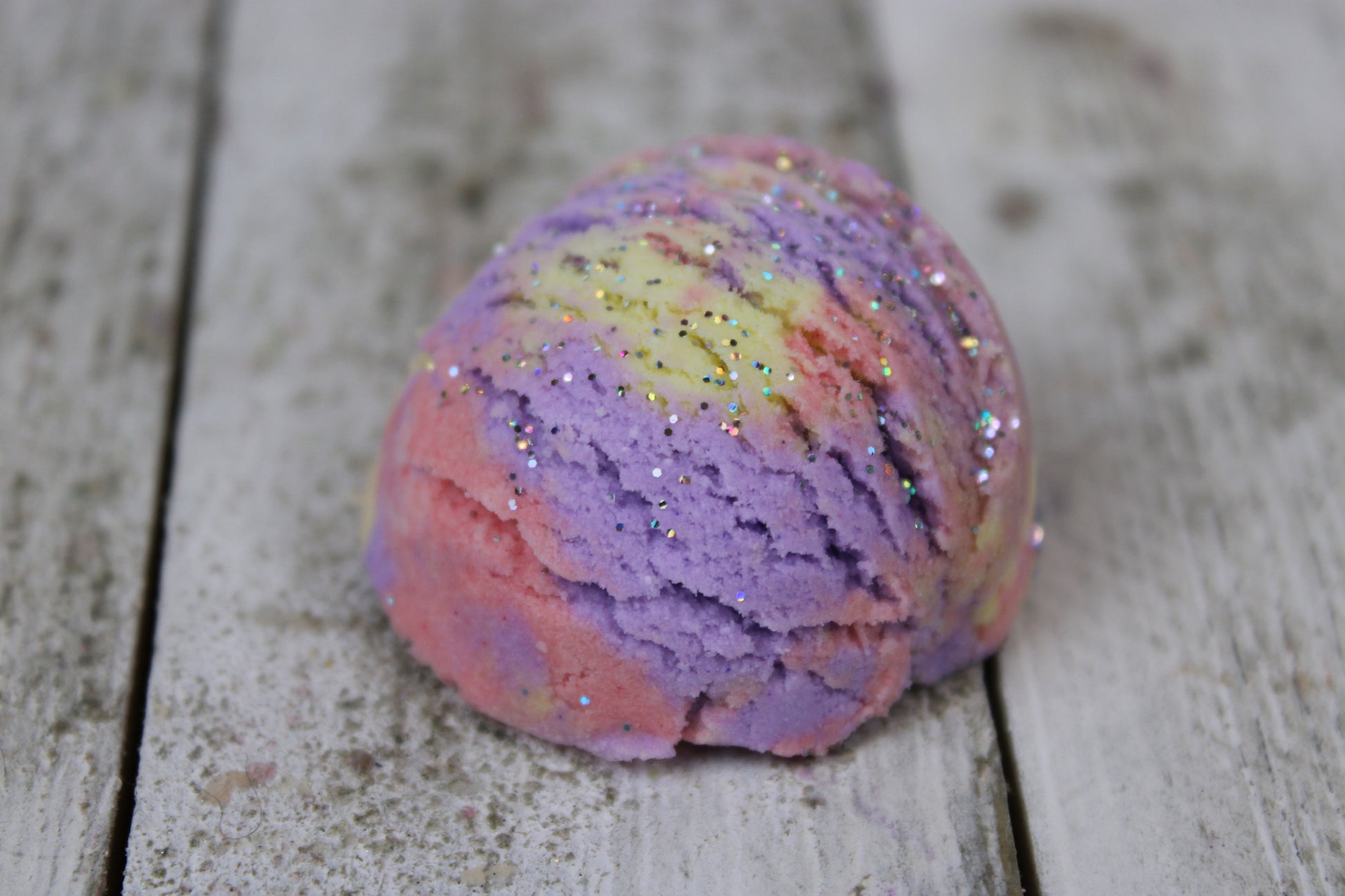 bubble bar up close. its pink, purple, and yellow with a silvery glitter.