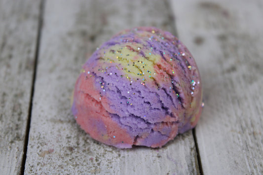bubble bar up close. its pink, purple, and yellow with a silvery glitter.