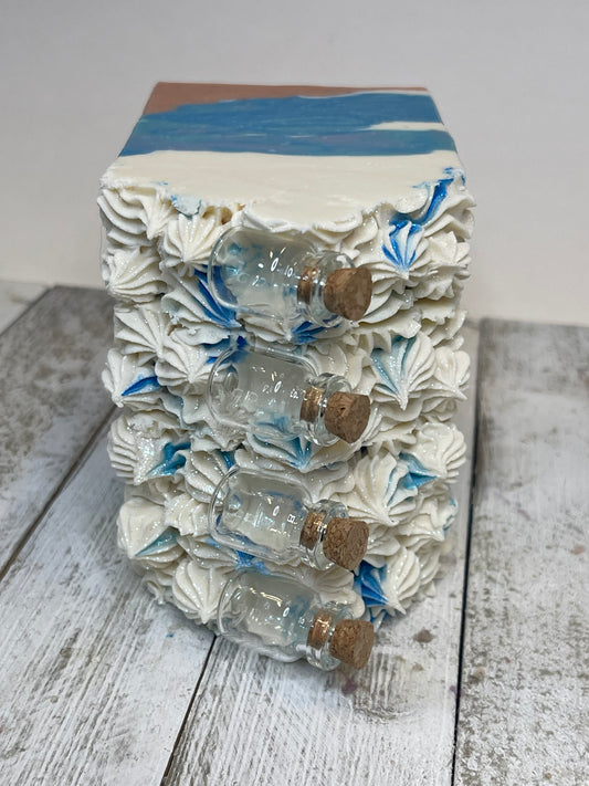 Message in the Bottle Soap Bar has glass bottles with corks on top the soap bars. The soap is inspired to look like sand with the ocean and crest of the waves. 